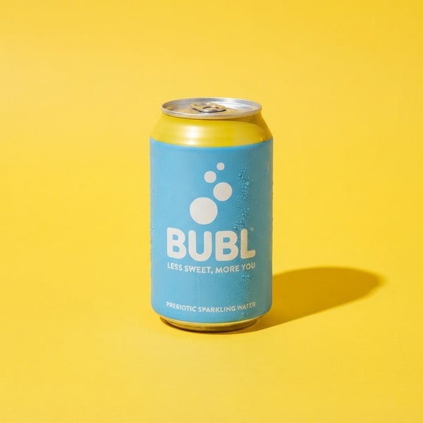 A drinks can photographed against a saturated yellow background with a hard shadow